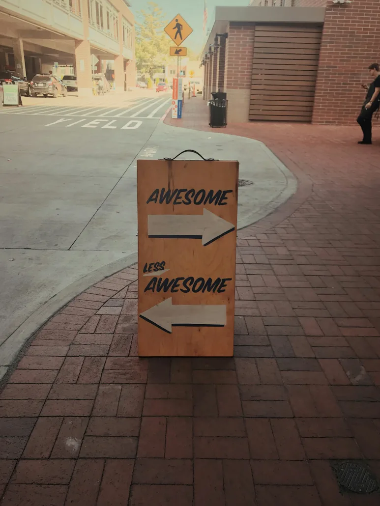 A sign that says "Awesome" pointing in one direction and "Less Awesome" pointing in another direction.